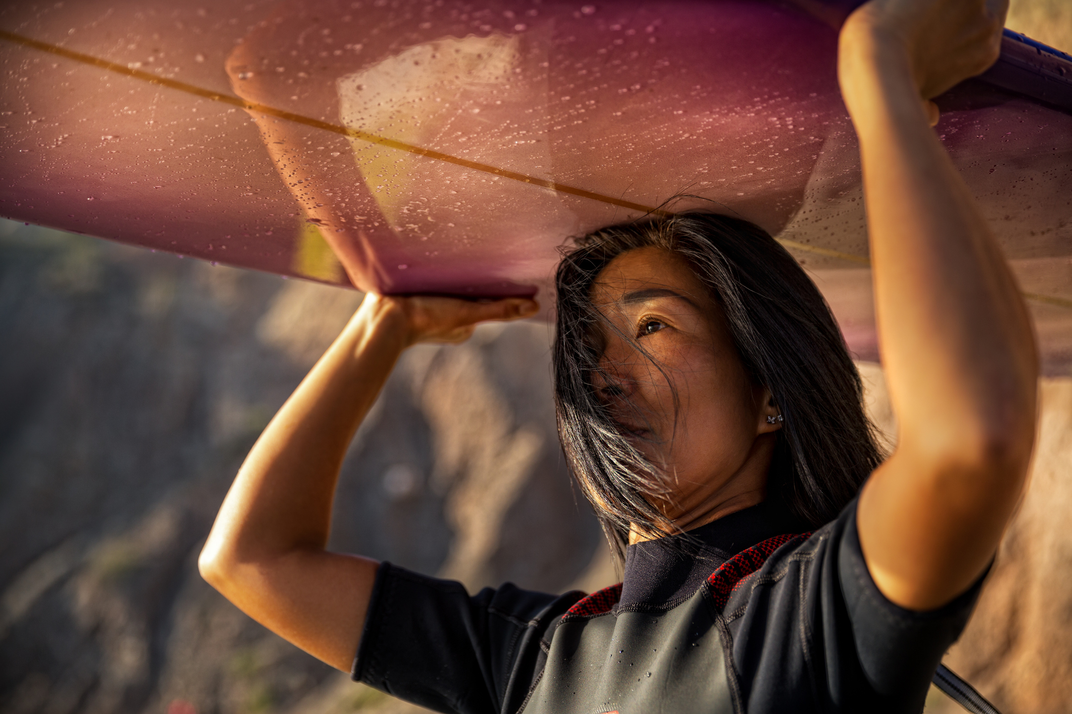 Surfer carrying board at golden hour