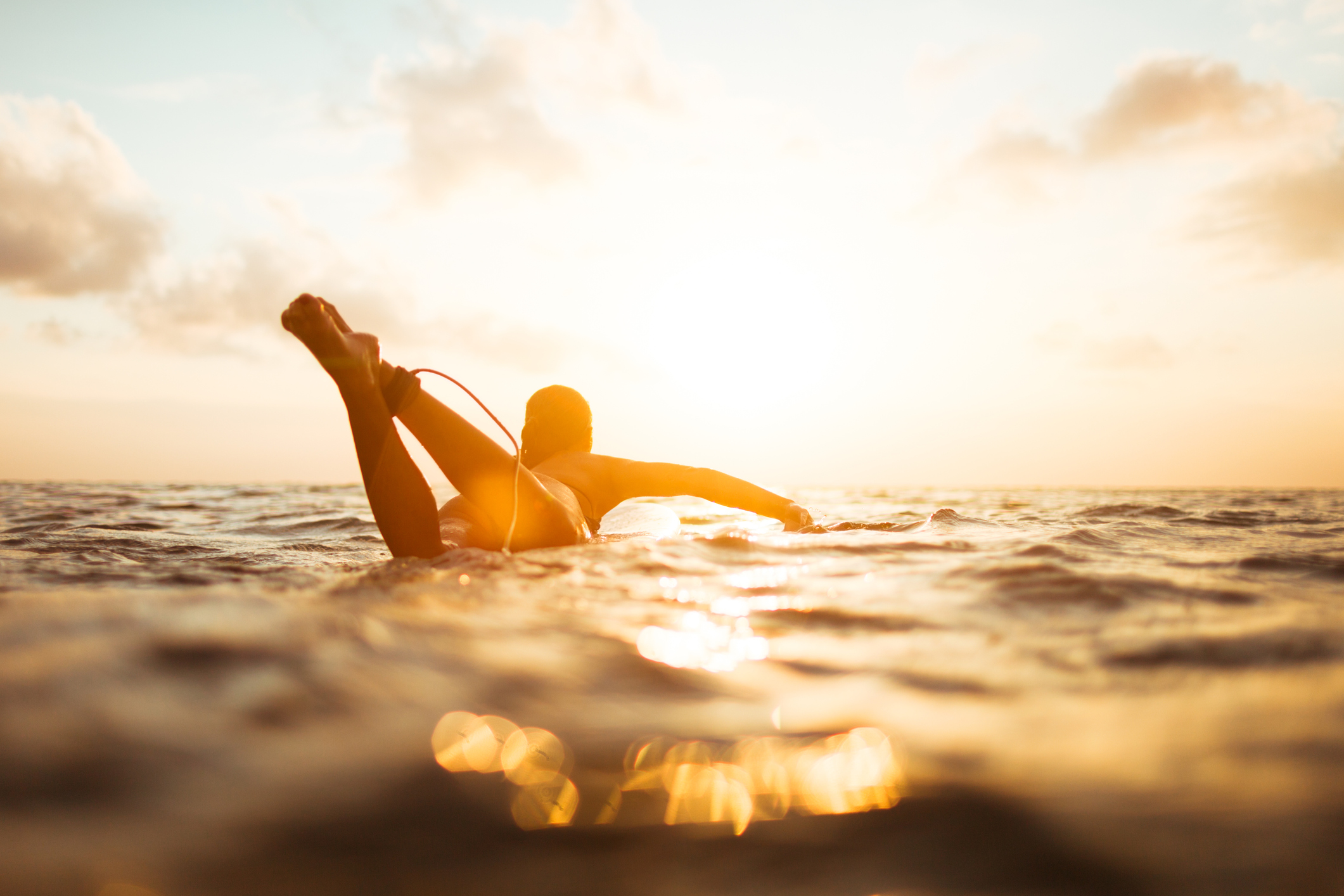 Surfer paddling at golden sunset