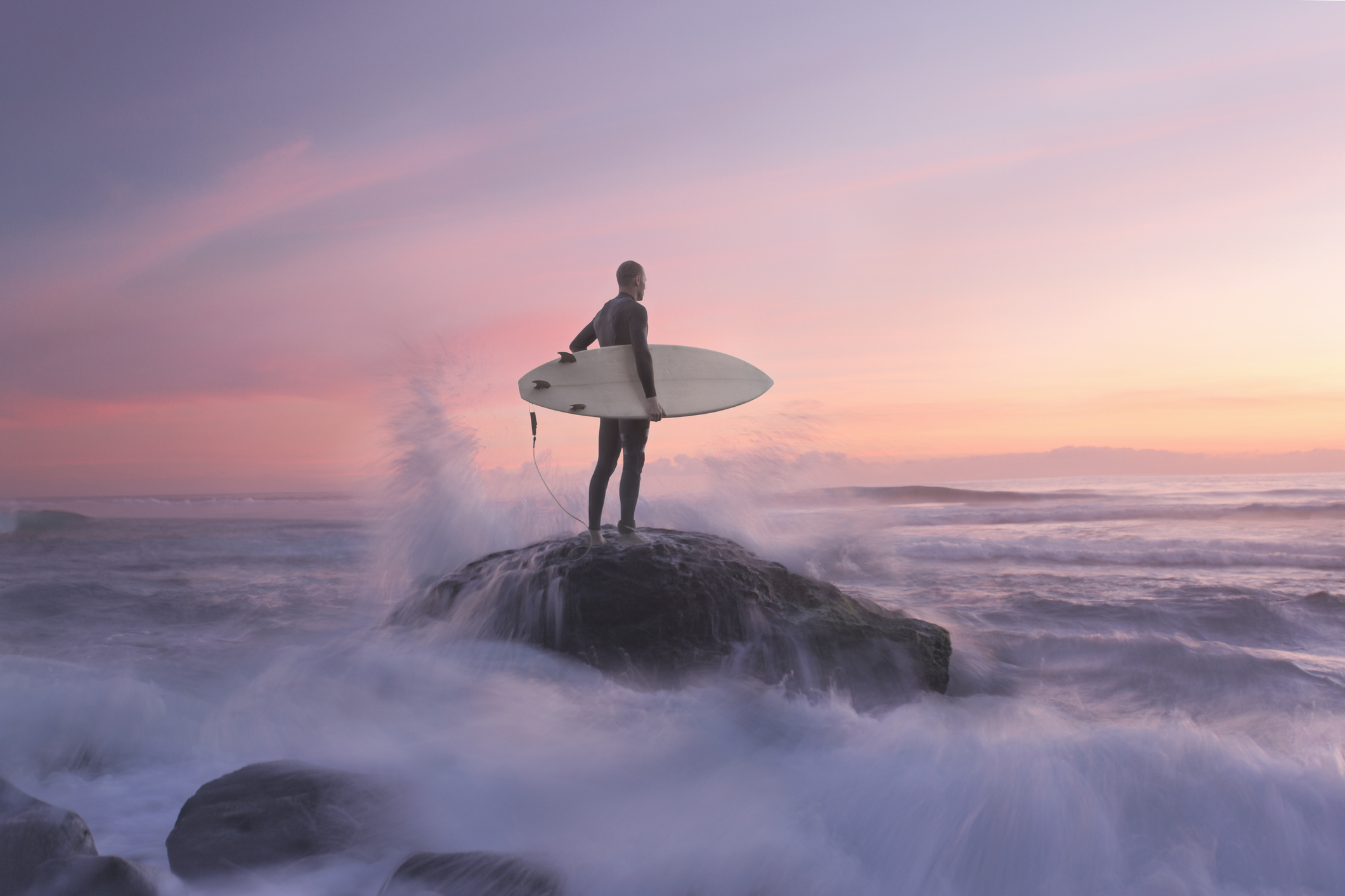 Surfer at sunset on rock